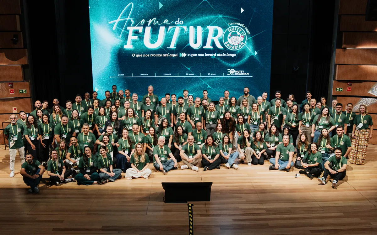 Foto de grupo dos participantes no palco, com o painel de LED ao fundo
