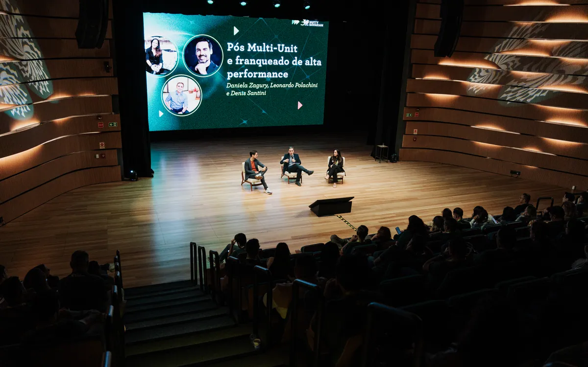 Debate no palco do Espaço Multiúso, com o painel de LED ao fundo e a plateia completa