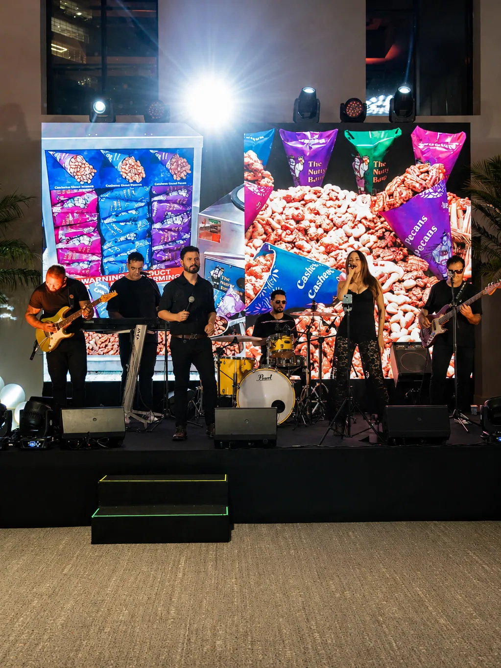 Banda ao vivo diante do painel de LED com os produtos da marca